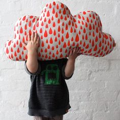 a small child is holding up a large cloud shaped pillow in front of his face