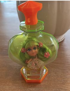 a small doll in a green bottle on a table