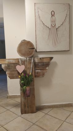 a vase with flowers in it next to a wooden angel