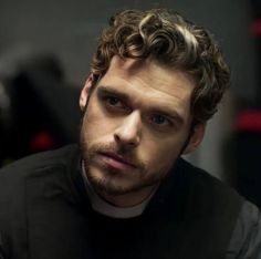 a man with curly hair wearing a black shirt