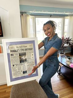 a woman in overalls holding up a newspaper with the word makaala's 7th birthday written on it