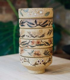 a stack of ceramic cups sitting on top of a wooden table