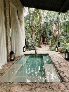 an outdoor pool surrounded by greenery and lanterns