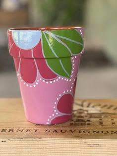 a pink flower pot sitting on top of a wooden table