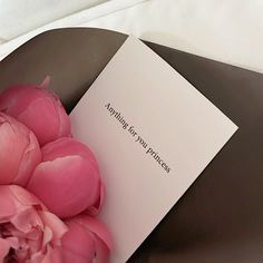 a bouquet of pink flowers sitting on top of a table next to a piece of paper