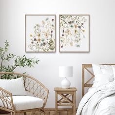 two paintings on the wall above a bed in a room with white walls and wooden flooring