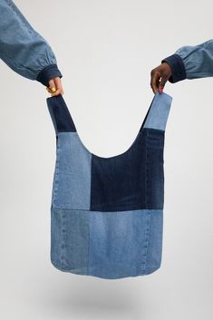 two hands holding up a bag made out of blue denims, with one hand in the pocket