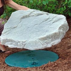 a woman kneeling down next to a large rock