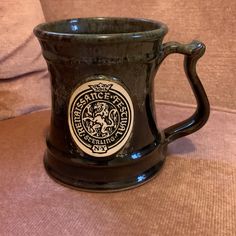 a black coffee mug sitting on top of a couch