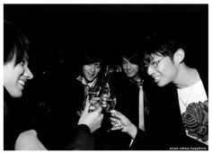 black and white photograph of three young men holding wine glasses in front of each other