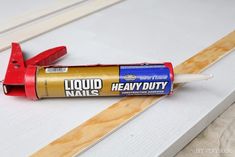 a close up of a paint roller and some glue on a table with wood planks