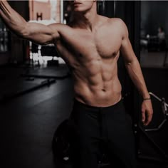 a shirtless man is holding his arm up in the air while standing next to a gym machine