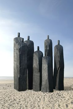 four sculptures on the beach with sky in background