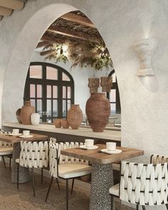 a dining area with tables and chairs, vases on the wall