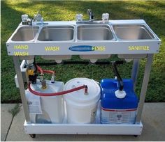 a double sink with two faucets attached to it on a cart in the grass