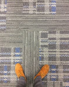 a person standing on a carpet with their feet in the air and wearing orange shoes