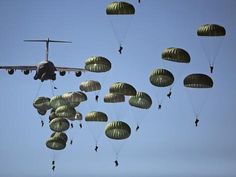 an airplane is flying in the sky with parachutes