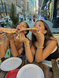 two women sitting at a table eating pizza