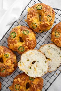 several bagels with cheese and jalapenos sitting on a cooling wire rack