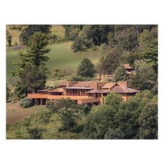 an aerial view of a large house in the middle of some trees and hills with lots of greenery