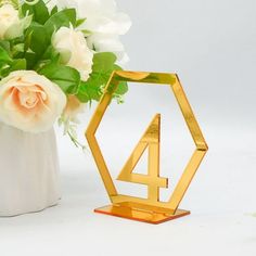 a vase filled with white flowers next to a golden number four