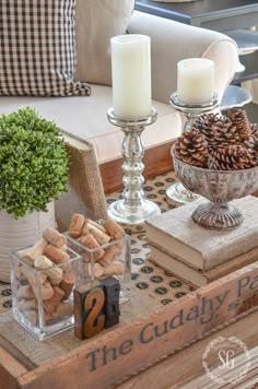 a coffee table with candles, books and other items on it in front of a couch