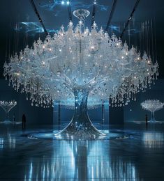 a large chandelier hanging from the ceiling in a dark room with people standing around it