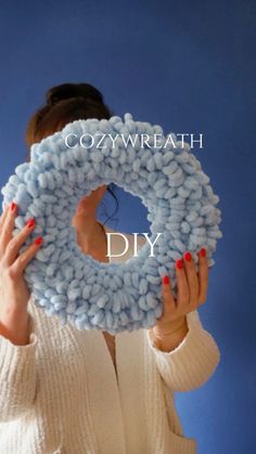 a woman holding up a knitted donut with the words cozweath diy on it