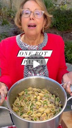 a woman holding a pot full of pasta on top of a table with a knife and fork in it