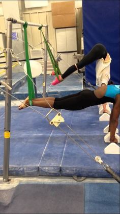 a woman is doing an acrobatic trick on the ropes in a gym