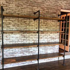 an empty room with brick walls and wooden shelves on the wall, along with metal pipe shelving