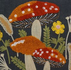 a close up of a design on a piece of cloth with flowers and mushrooms in the background