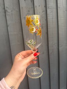 a hand holding a wine glass with sunflowers painted on it and the bottom