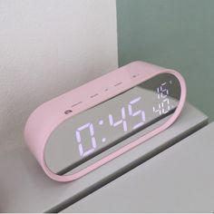 a pink alarm clock sitting on top of a dresser