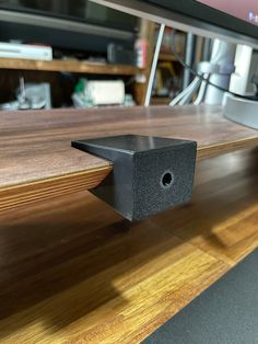 a black speaker sitting on top of a wooden shelf