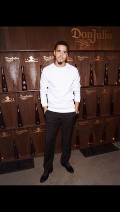 a man standing in front of a wall full of bottles