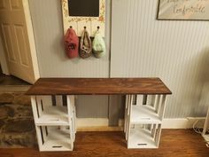 a wooden table sitting in front of a wall with shoes on the shelf next to it