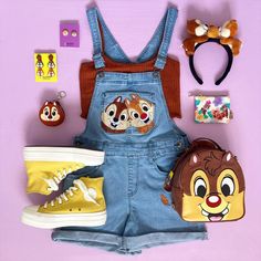 a pair of denim overalls with cartoon characters on them and other accessories laid out next to it