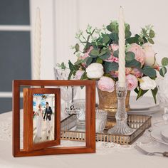 the table is set with flowers, candles and two framed photos on it's sides