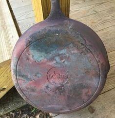 an old frying pan sitting on top of a wooden floor next to a door