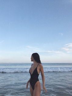 a woman in a bathing suit walking into the ocean