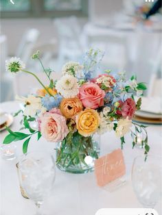 a vase filled with lots of flowers on top of a table next to plates and glasses