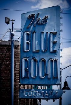 the blue room sign is hanging from the side of a building in front of a street light