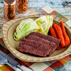 a plate with meat, cabbage and carrots on it next to a knife and fork