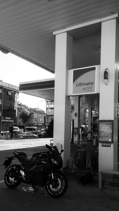 a motorcycle is parked in front of a gas station with no one on the bike