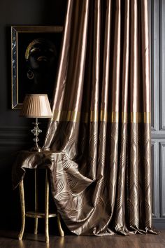 a lamp is next to a curtain in a room with dark walls and wooden floors