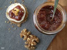 a jar filled with jelly and nuts on top of a blue cloth next to a cookie