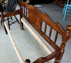 a wooden bed frame sitting on top of a floor next to a chair and table