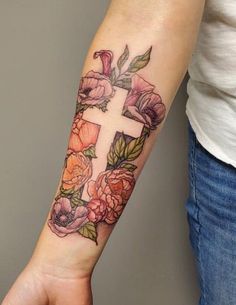 a woman's arm with flowers and a cross tattoo on the left side of her arm