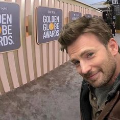 a man standing in front of a golden globe awards sign